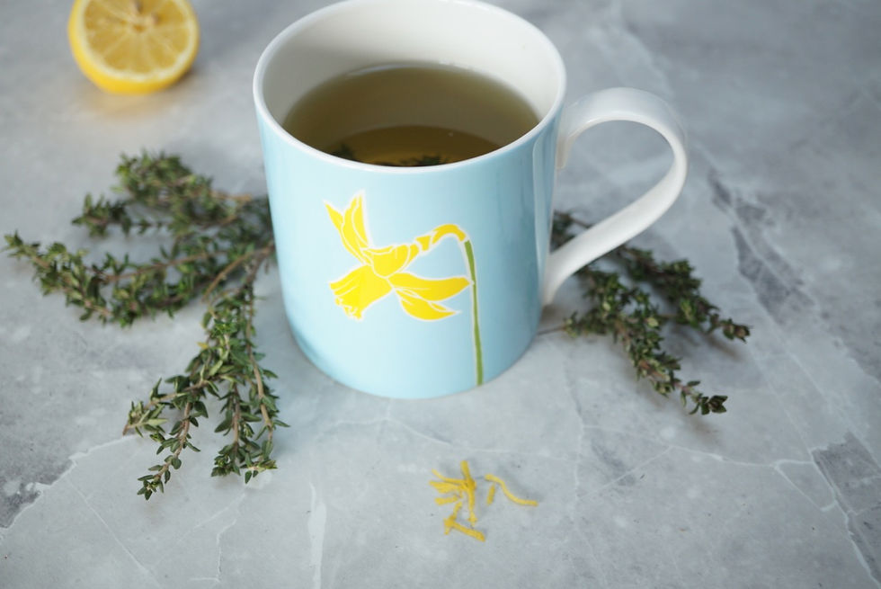 A daffodil mug with sprigs of thyme and some lemon