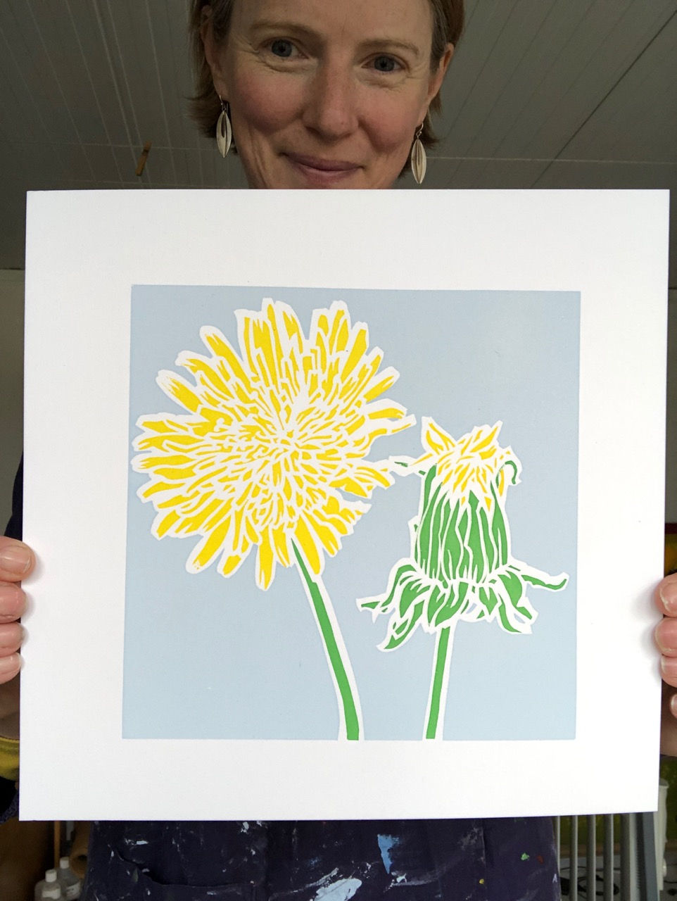 A lady holding an art print of a yellow dandelion