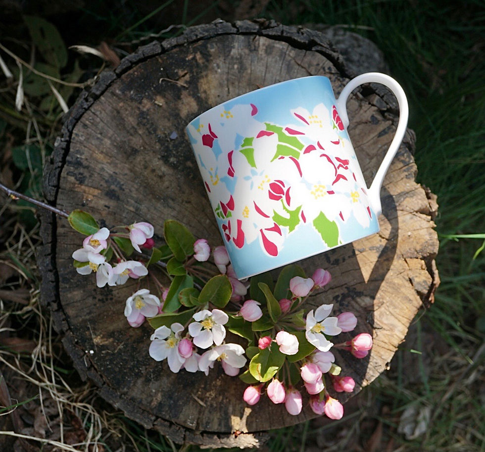an apple blossom mug lying on a log with blossom flowers