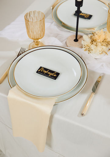 Luxury wedding reception table setting with elegant white floral centerpiece, gold-rimmed plates, polished gold cutlery, and crystal goblets with gold accents, styled for a sophisticated and romantic wedding celebration in Orange County, California