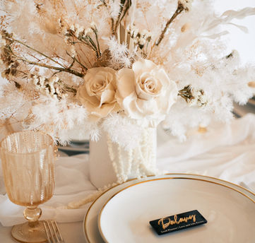 Chic and timeless reception table setup with white blooms, gold-accented dinnerware, sparkling goblets, and gold flatware, beautifully arranged by an Orange County wedding planner.