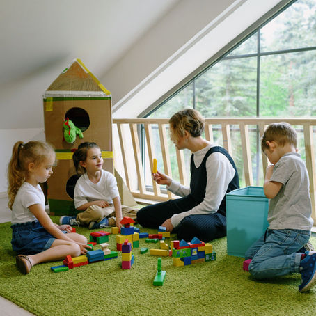 A teacher guiding young children as they build with colorful wooden blocks.