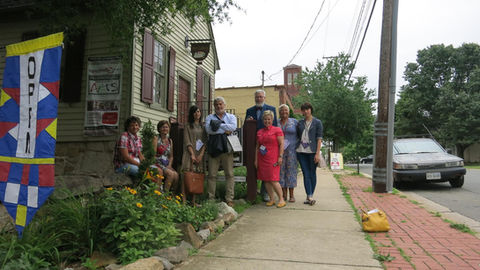 Group of diverse people standing outside historic building on a sidewalk.