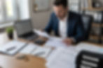 Property investor reviewing rental property financial documents at a desk with invoices, receipts, and reports, illustrating hidden property management fees affecting rental property profitability.