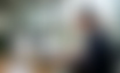 A professional property manager in a modern office reviewing rent payments on a laptop and tablet.