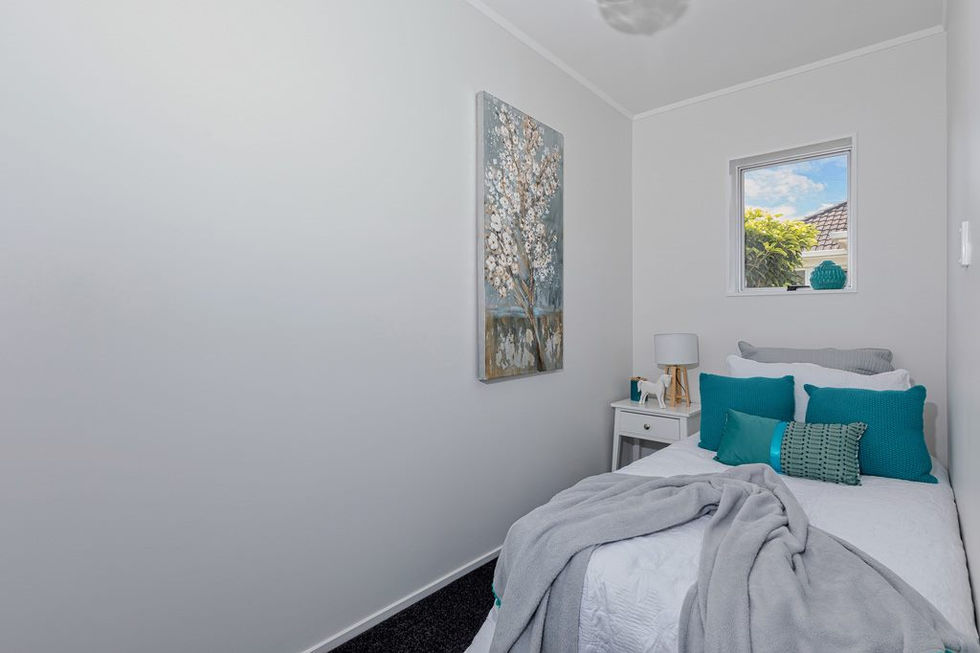 Bedroom Renovation with white walls, bed, pillows, artwork, and window, Auckland Builder.