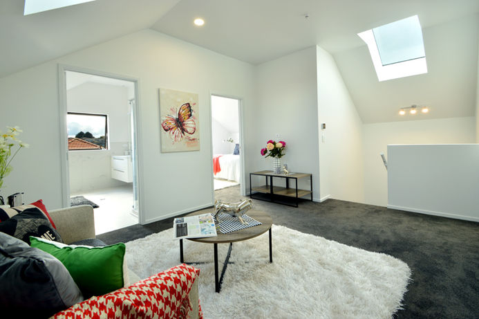 New Build home in Auckland with a Modern living room with skylight, artwork, and white walls. Auckland Builder