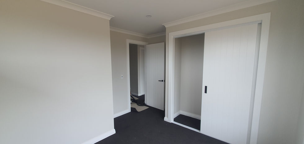 New Build home in Auckland with a Interior view of a room with white doors, walls and dark carpet.