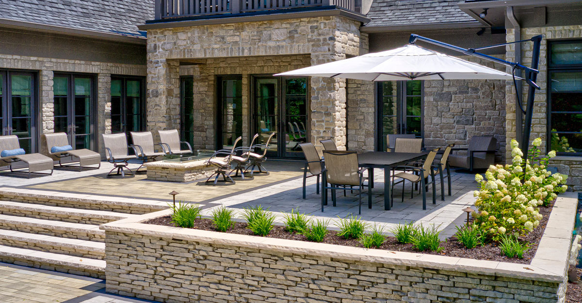 Large raised patio with dining area, seating wall, and umbrella shade.