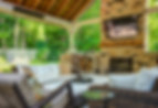 Covered outdoor living space with seating area and stone fireplace.