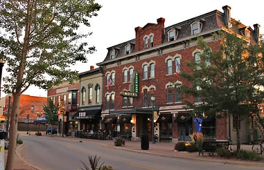 Historic brick buildings line a street with a "HOTEL" sign at sunset.