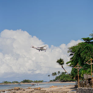 Small airplane flying above a tropical island beach on the way to San Pedro, Belize