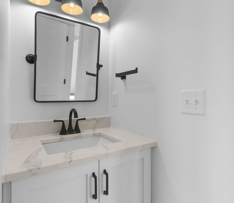 Modern bathroom vanity with white cabinets, sink, and mirror