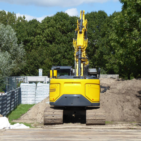 Yellow excavator clearing a route through wooded land