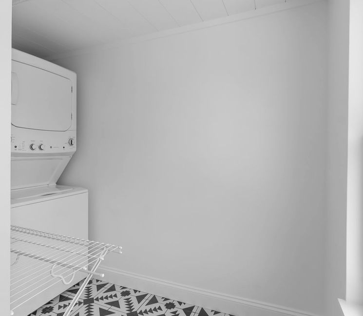Stacked washer/dryer in laundry room with patterned floor