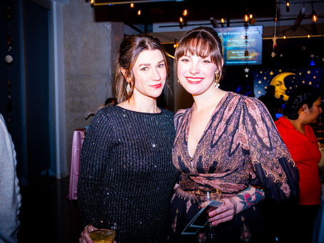 Two guests smiling for a photo at a company holiday party with festive lighting