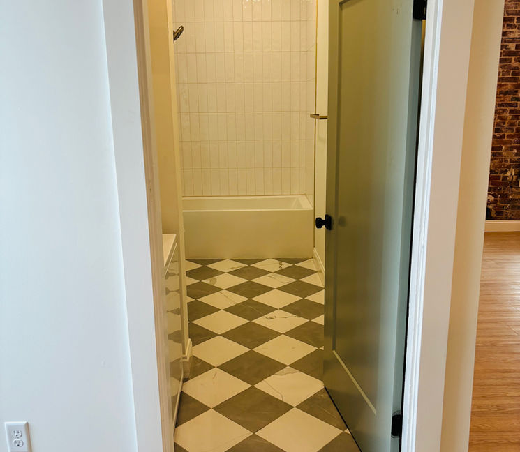 Open doorway to bathroom with checkered floor and white bathtub