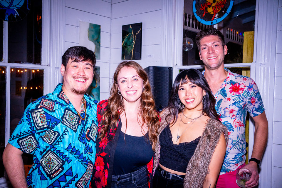 Four friends smiling together, posing for a photo. Party attire inside the venue.