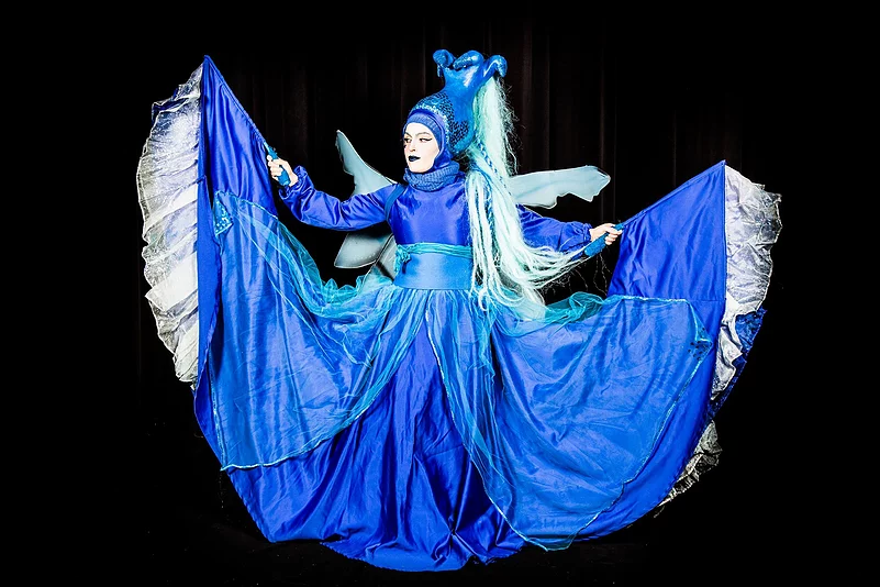 Bleue Azure, échassière animée en bleu profond, améliorant l'ambiance avec sa performance théâtrale lors d'une soirée à thème.