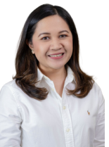 Woman smiling, wearing glasses and a light pink t-shirt with a logo. Brown hair, relaxed expression. Plain background.