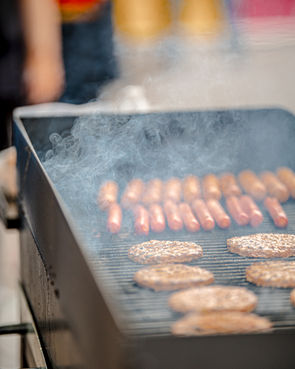 Grill with hot dogs and burgers cooking at a food stand during Bike Night at Goshen First Fridays.