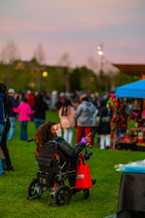 Crowd gathered on the lawn at the downtown Elkhart Cinco de Mayo celebration, and a person in a wheelchair in the foreground.