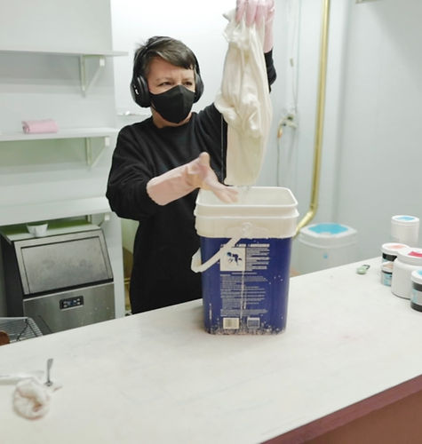 Woman is holding a dripping white shirt above a bucket before tie-dying