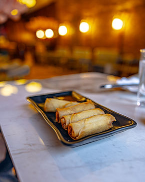 A plate of egg rolls in a restaurant, on the table.