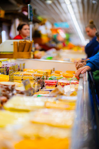 Shoppers browsing a long counter of packaged cheese inside the South Bend Farmers Market.