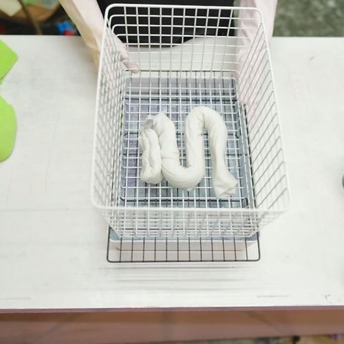 The folded shirt is placed in a white metal basket