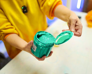 A hand is opening a jar of green screen printing ink
