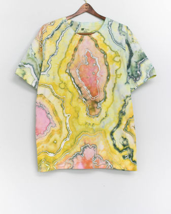 A geode died shirt is hanging on a wooden hanger against a white wall