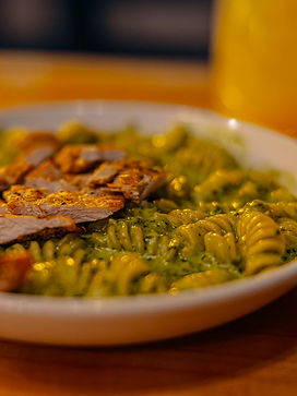 A bowl of pesto pasta with grilled chicken on top.