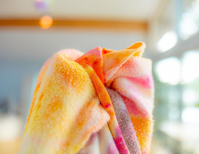 Close-up of brightly dyed bamboo fleece fabric folded with visible fuzzy texture, showing soft pastel and orange tones.