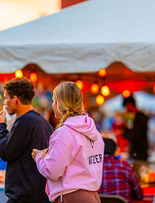 Crowd at Civic Plaza during Cinco de Mayo in downtown Elkhart with food tents and string lights at dusk