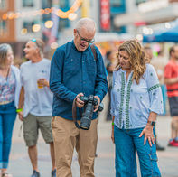 Photographer reviewing images with a couple at an outdoor event, showing real time interaction when deciding how to choose an event photographer