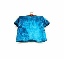 A blue tie dye shirt is hanging on a white wall after being dyed in a bin, using fiber reactive dye.