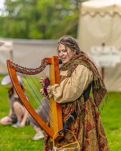 A heart player is performing as a vendor at the Niles Renaissance faire.