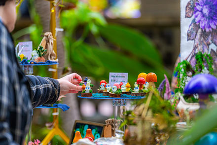 Detailed view of small glass mushroom sculptures and moss displays at an Indiana art market booth.