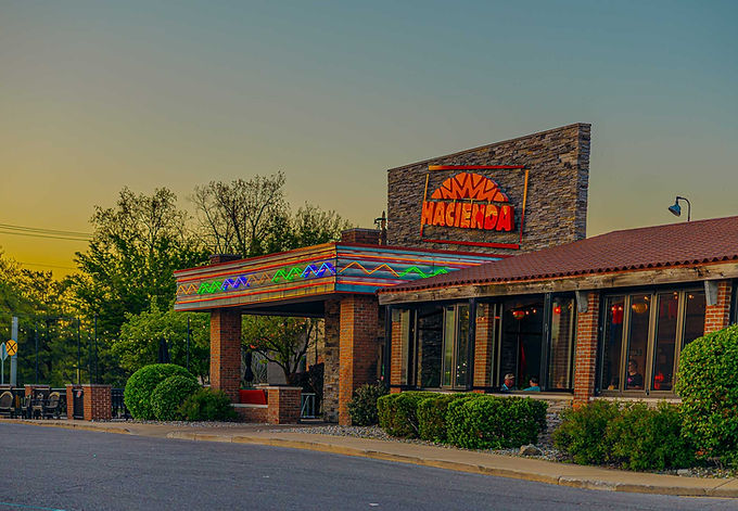 Exterior of Hacienda Mexican Restaurant in Elkhart, Indiana at sunset, featuring colorful neon trim and brick facade.