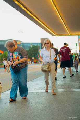 A woman is walking under the overhang at the front entrance of the learner theater