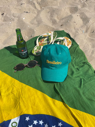 Praia, canga da bandeira do Brasil com um boné escrito brasileiro, um par de havaianas e óculos