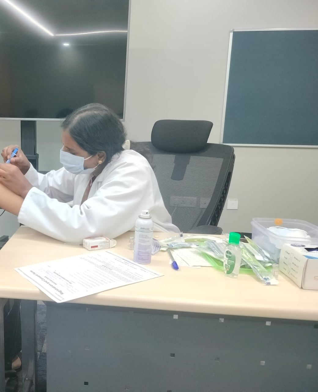 Nurse preparing a dose with consent forms on the desk