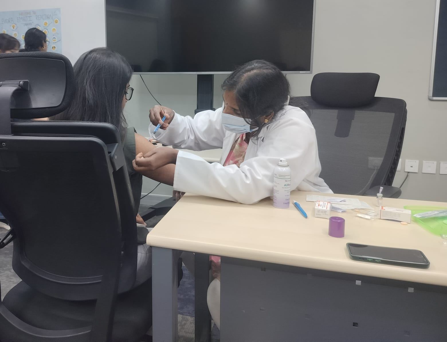 Nurse vaccinating an employee at a desk