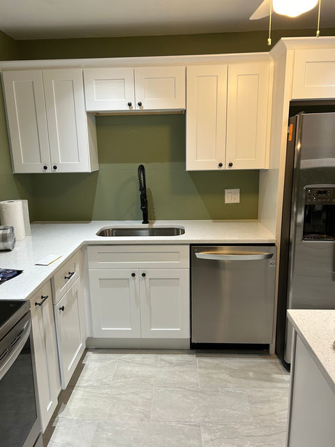 custom kitchen with white shaker custom wood cabinets and quartz stone countertops and green wall