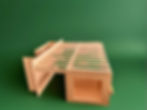 This is an image of cabinets. specifically an extendable bed cabinet made out of maple ply. the bed is currently extended and resting on the cabinet across from it. that cabinet is designed to support the bed extension and house the kitchen. the cabinets are of minimalist design and set against a green backdrop.