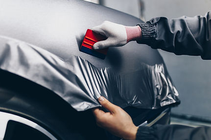 Car wrapping specialist putting vinyl foil or film on car. Selective focus. .jpg