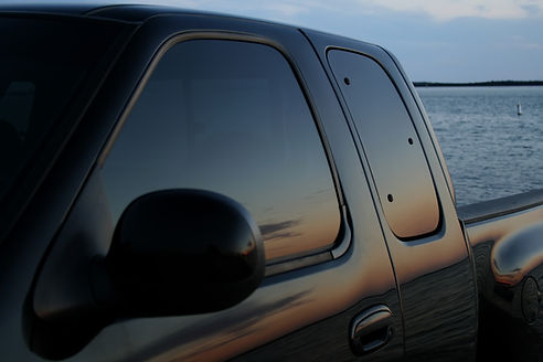 american black truck parked at the beach with a sunset reflection in the tinted window.jpg