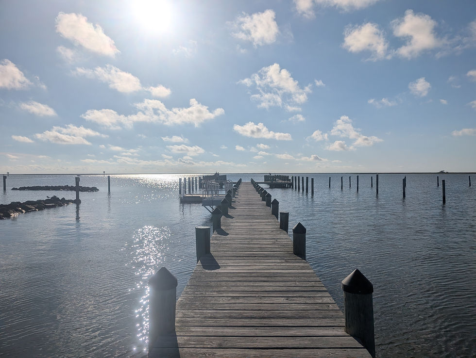 a pier stretches out into the water as the sun begins to set