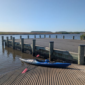 a kayak sits on a boat ramp with marsh in the distance